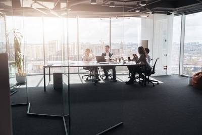Ein Team von Geschäftsleuten, das sich im Büro mit Panoramafenstern zu einem Meeting trifft