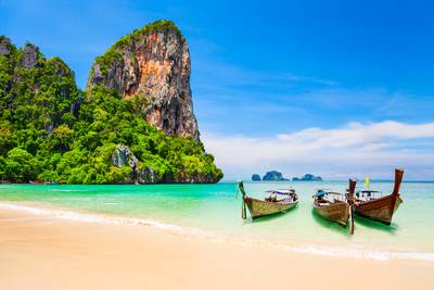 Boote am Schönheitsstrand mit Kalksteinklippen und kristallklarem Wasser in Thailand