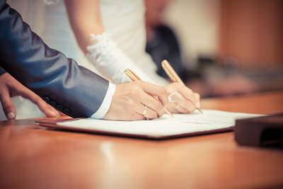 Hochzeitspaar unterschreibt gemeinsam ein Dokument